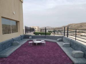een balkon met een bank en 2 tafels op een tapijt bij شالية نفرتيتي : فخامة المكان وجمال الاطلالة in Jeddah