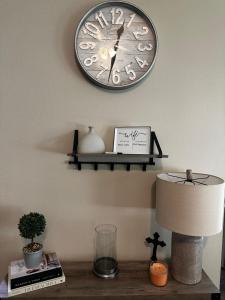 a clock on a wall above a table with a lamp at The Coffee Pitstop! in Saint Robert