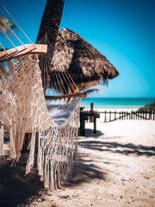 a hammock on a beach with an umbrella and the ocean at Utopia Guesthouse & Yoga Studio beachfront home in El Cuyo