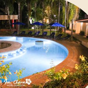 een groot zwembad met blauwe parasols en stoelen bij Hotel Campestre Santa Clara in San Juan Bautista Tuxtepec
