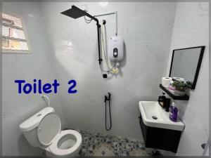 a white bathroom with a toilet and a sink at Modern HS Sweet Homestay Kuantan in Kuantan