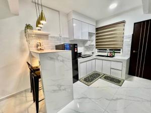 a kitchen with white cabinets and a black refrigerator at Modern HS Sweet Homestay Kuantan in Kuantan