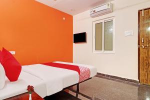 a bedroom with a bed with an orange wall at Super OYO Flagship Sai Mansion in Hyderabad