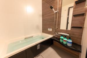 a bathroom with a bath tub and a sink at Irodori Hotel MOMO in Fukuoka