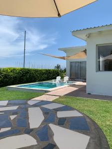 un patio trasero con piscina y una casa en Tropical Vibes Beach House, en San Rafael