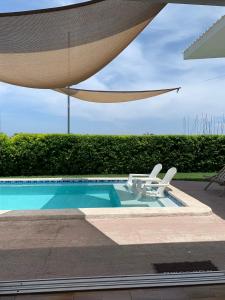 a swimming pool with two chairs and a umbrella at Tropical Vibes Beach House in San Rafael