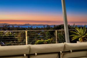 a couch sitting on a balcony with a sunset at Sanctuary Spaces - Sundowner in Byron Bay