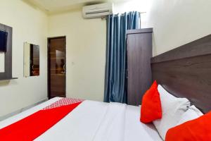 1 dormitorio con 1 cama con almohadas rojas y blancas en OYO Flagship Hotel Pink Orchid en Kota