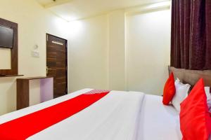 Schlafzimmer mit einem weißen Bett und roten Kissen in der Unterkunft OYO Flagship Hotel Pink Orchid in Kota