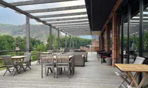 un patio con tavoli, sedie e montagne sullo sfondo di Hotel Stancia Kazbegi - City Center a Kazbegi