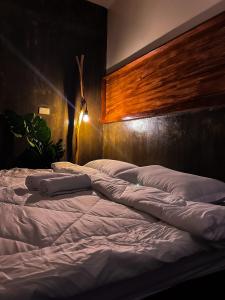a large bed with white sheets and a wooden headboard at M-Resort Siargao in General Luna +2 photos
