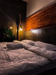 a large bed with white sheets and a wooden headboard at M-Resort Siargao in General Luna