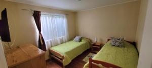 Habitación pequeña con 2 camas y ventana en Hospedajes Roma en Valdivia