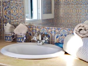 lavabo blanco en el baño con espejo en Maison d'Hote Domaine El-Manar, en Zarzis