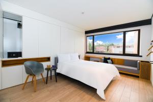1 dormitorio con 1 cama blanca grande y 1 silla en Stey Sanlitun Boutique Hotel, en Beijing