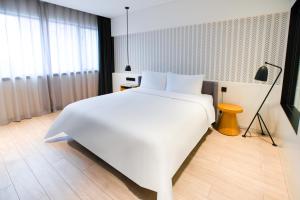 a bedroom with a large white bed and a lamp at Stey Sanlitun Boutique Hotel in Beijing