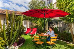 a woman sitting at a table under a red umbrella at Hotel La Cartuja in Quito