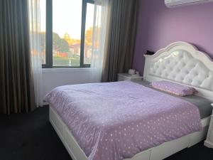 a bedroom with a white bed with purple sheets and a window at Private Rooms in Clayton South Near Monash Uni in Clayton North