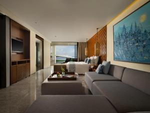 a living room with a couch and a room with a tv at Anantara Uluwatu Bali Resort in Uluwatu