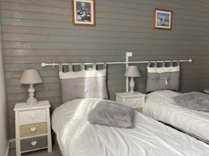 2 Einzelbetten in einem Schlafzimmer mit 2 Lampen in der Unterkunft Le Chalet de Larcat in Larcat