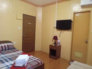 a small room with a bed and a television at JAZ-M Pensionhouse in Tagbilaran City
