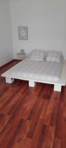a white bed in a room with a wooden floor at Le Petit Nid in Saint-Loubès