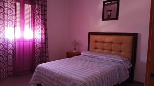 a bedroom with a bed and a window with a purple curtain at Cazorlasalud in Santo Tomé