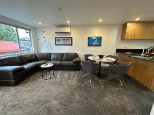 a living room with a black leather couch and a table at Plymouth Central City 2 Bedroom Apartments in New Plymouth