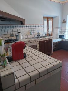 una cocina con encimeras de azulejos blancos y un taburete rojo en Il Casale, en Penna San Giovanni