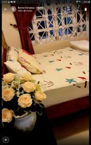 a bedroom with a bed with flowers in a vase at BONNIE HOMESTAY Mui Ne in Mui Ne