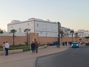 een groep mensen die door een straat voor een gebouw lopen bij Dar Azam in Essaouira