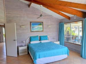a bedroom with a blue bed and a window at Sands Villas in Rarotonga