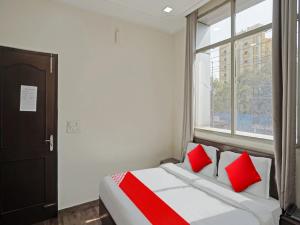 Schlafzimmer mit einem Bett mit roten Kissen und einem Fenster in der Unterkunft Hotel Grand Stay in Ghaziabad