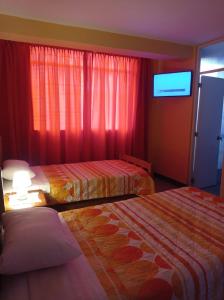 Habitación de hotel con 2 camas y TV de pantalla plana. en Hostal Madrid, en Pisco