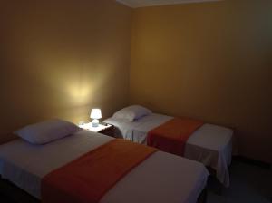 Habitación con 2 camas y una lámpara en una mesa. en Hostal Madrid, en Pisco