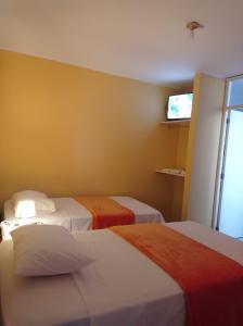 a hotel room with two beds and a television at Hostal Madrid in Pisco