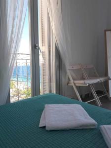 a bedroom with a bed and a window with a chair at Seaside Serenade 1, suite in Ermoupoli