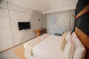 a bedroom with a white bed and a television at Giraffe Beach Hotel in Dar es Salaam