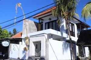 une maison blanche avec un palmier en face dans l'établissement Amour Eternel Villa, à Nusa Penida