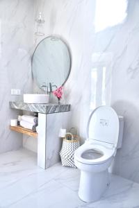 La salle de bains blanche est pourvue de toilettes et d'un miroir. dans l'établissement Amour Eternel Villa, à Nusa Penida