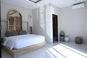- une chambre blanche avec un grand lit et un miroir dans l'établissement Amour Eternel Villa, à Nusa Penida