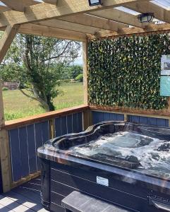 a hot tub on a deck with a hedge at Coolaness Glamping in Irvinestown