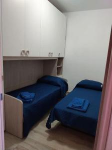 una camera con due letti con lenzuola e armadi blu di LA Pavoncella a La Maddalena