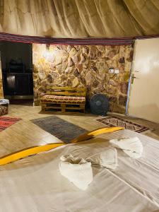 a bed in a room with a stone wall at Pink city cottage in Wadi Musa
