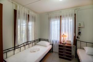 two beds in a room with two windows and a lamp at Solomon House in Kritharia