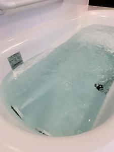 a bath tub filled with blue water in a bathroom at Condominium Panoramique Motomachi in Hakodate