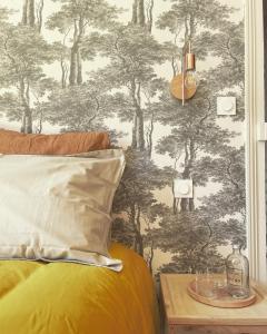 a bedroom with a bed with a forest wallpaper at Maison Mandarine in Bellerive-sur-Allier