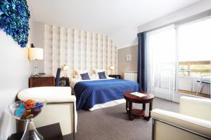 a bedroom with a blue bed and a large window at Carnac Lodge Hotel & Spa in Plouharnel