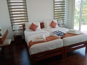 two twin beds in a room with windows at Sandy Shores in Trincomalee