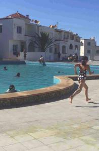 una mujer corriendo por una piscina con un frisbee en Appartement familial paisible, en Tánger